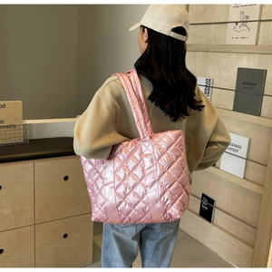 Gros plan d'un sac cabas matelassé rose porté à l'épaule dans un cadre de vie réel