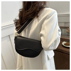 Detail of black saddle bag with wavy flap and black and white wide woven strap