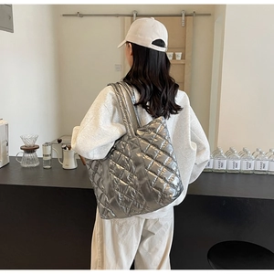 Vue détaillée du sac cabas matelassé argenté en tissu métallisé porté par un mannequin