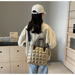 Detail of a gold quilted tote bag with black handles in a stylish minimalist setting