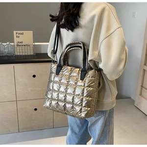 Detail of champagne gold quilted tote bag with square stitching and black shoulder strap