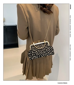 Model showing the black pearl evening bag with gold metal clasp and chain strap