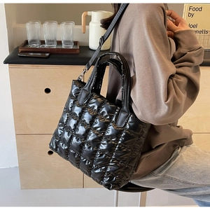Détail d'un sac cabas noir matelassé brillant avec bandoulière réglable et texture chic