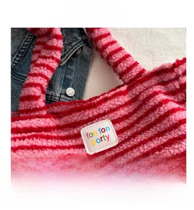 Detail of pink and red striped plush tote bag with a white square leather logo patch