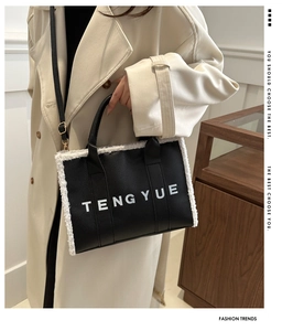 Detail of black leather tote with white faux fur trim and TENGYUE logo held by a model