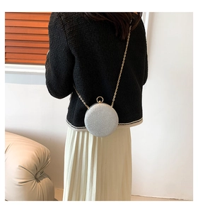 Detailed view of a silver glitter round clutch with a gold chain and metal ring handle