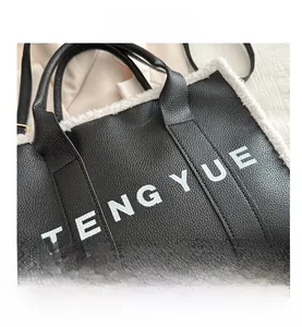 Detail of black pebbled leather tote with white faux shearling trim and TENGYUE logo
