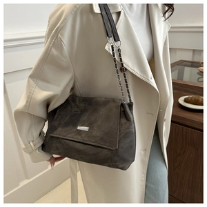 Close-up of matte PU leather tote with silver logo and chain strap on a model