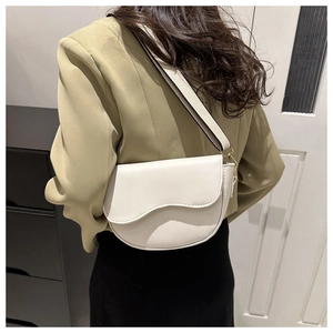 Creamy white saddle shoulder bag with wide strap styled on a model in khaki blazer