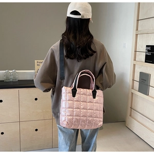 Sac fourre-tout matelassé rose avec anses noires porté par un mannequin chic