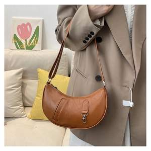 Brown faux leather crescent bag with retro texture shown on a model in a cozy setting