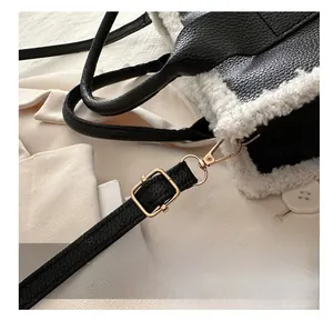 Detail of golden metal lobster clasp and adjustable buckle on leather plush tote bag