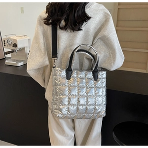 Détail du sac fourre-tout argenté matelassé avec poignées noires et bandoulière réglable