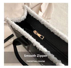Detail of smooth gold zipper and white faux shearling trim on black leather tote bag