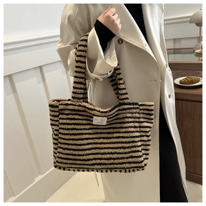 Detail of plush striped tote bag featuring a decorative fon fon party patch and soft texture