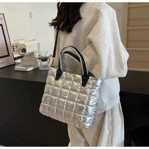 Quilted silver tote bag detail with large grid pattern and black leather handles