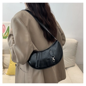 Detail of black crescent shoulder bag featuring cracked leather texture and silver carabiner