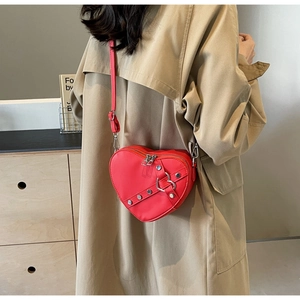Detail of red heart-shaped crossbody bag with silver studs and heart metal buckle