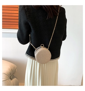 Detail of a round champagne gold sequin evening bag with a metal ring clasp and chain