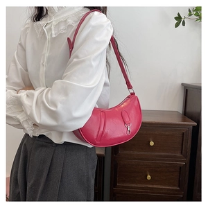 Detail of red crescent shoulder bag featuring wrinkled leather texture and silver zipper