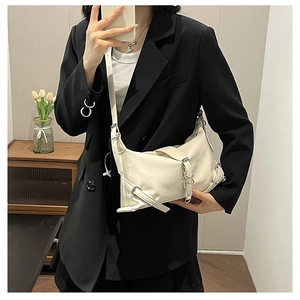 Mirror selfie showing the white leather crossbody bag with metal ring and buckle details