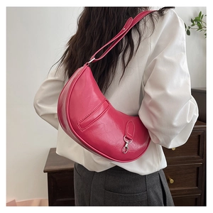 Close-up of a pink crescent-shaped shoulder bag with glossy crinkled leather texture