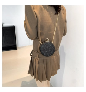 Dettaglio borsa rotonda nera glitterata con tracolla a catena dorata su modella