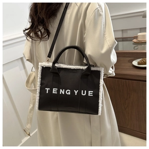 Detail of black leather tote with white faux fur trim and branded lettering print
