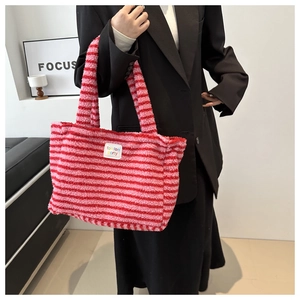 Detail view of pink and red striped plush tote bag with a small woven label design