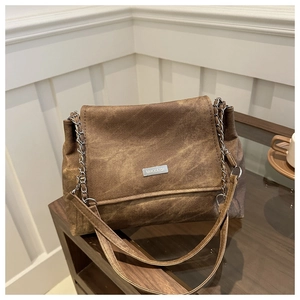 Detailansicht der dunkelbraunen Vintage-Tasche mit silberner Metallplakette und Kettenriemen