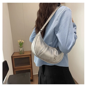 Close-up of the silver crescent shoulder bag featuring a metallic patent finish