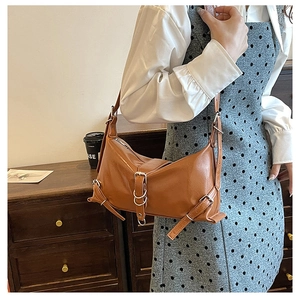 Close-up of vintage brown PU leather shoulder bag with silver metal rings and buckles
