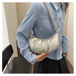 Detail of silver crescent shoulder bag featuring metallic finish and textured wrinkles