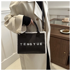Close-up of black leather tote bag with white shearling trim and TENGYUE logo detail