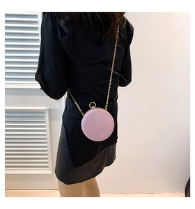 Détail du petit sac rond rose perlé avec bandoulière chaîne dorée sur tenue noire