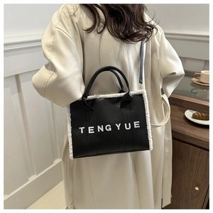 Detail of black faux leather tote bag with white plush trim and TENGYUE brand lettering