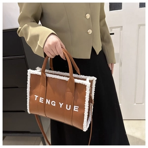 Brown tote bag with white faux fur trim and shoulder strap shown on a model