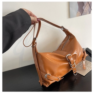 Detail showing vintage caramel faux leather texture and silver buckle on hobo bag