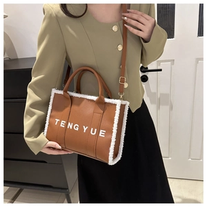Close-up of brown textured leather tote with white faux shearling trim and logo