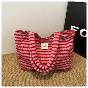 Détail d'un sac cabas en peluche à rayures rouge et rose avec écusson en similicuir