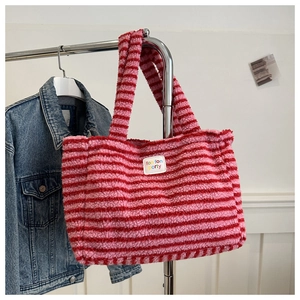 Close-up of pink and red striped plush tote bag showing soft faux fur texture and logo tag