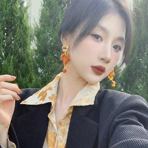 Detail of vintage grape-style orange beaded earrings with retro gold accents worn by a model