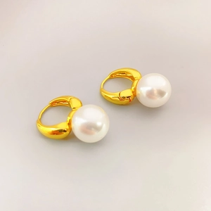 Gros plan détaillé de boucles d'oreilles en laiton doré avec d'élégantes perles blanches