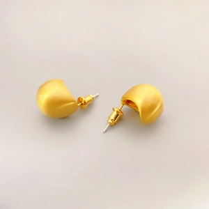Detail of golden puff earrings featuring a fine brushed matte finish and 3D crescent design