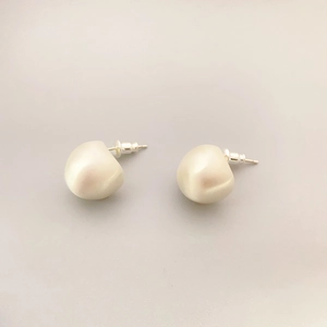 Elegant baroque pearl stud earrings with 925 silver needles on a minimalist background