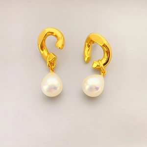 Détails de boucles d'oreilles dorées avec perles blanches en goutte et reflets irisés