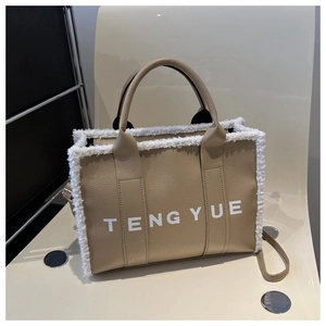 Detail of camel lychee leather tote bag featuring white faux fur trim and branded handles