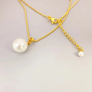 Detail of elegant gold necklace featuring a white pearl pendant and adjustable chain clasp