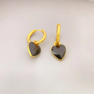 Gros plan de boucles d'oreilles créoles dorées avec pendentifs cœur en émail noir