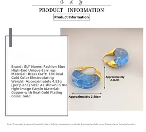 Detail of blue resin C-shaped hoop earrings with gold foil flakes and 18K gold plating